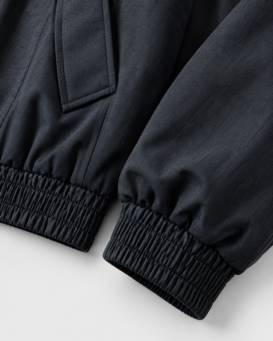 Black | Close-up of the elastic hem detail on the black zip-up jacket