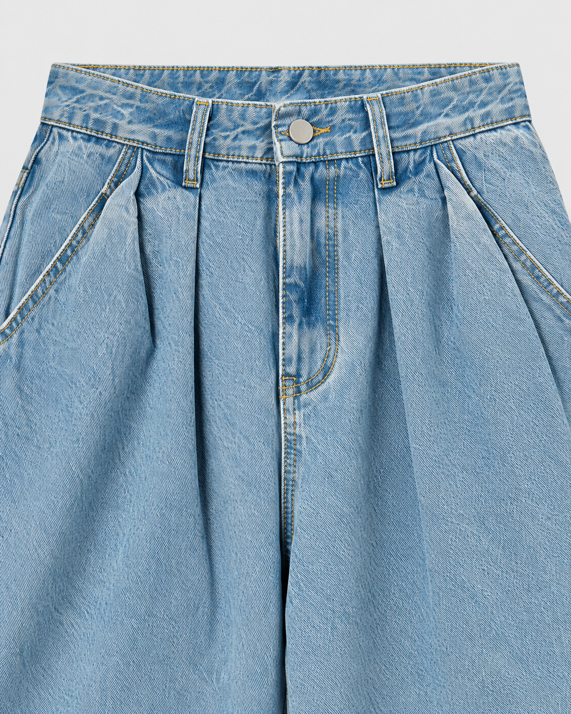 Medium | Close-up of waistband and front pleats on medium-blue wide-leg jeans