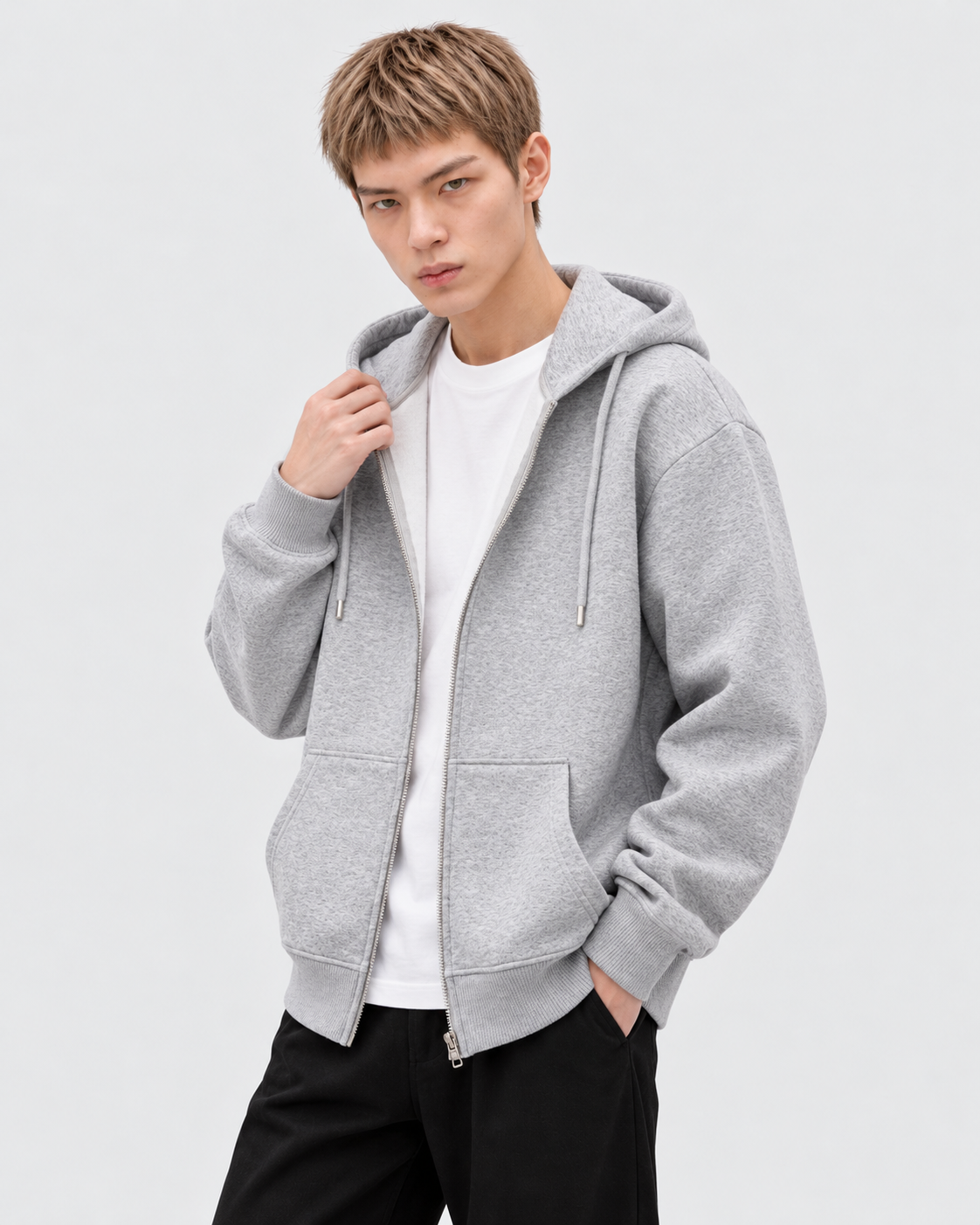 Heather Gray | Male model wearing a heather gray zip-up hoodie, three-quarter studio pose with hand at collar