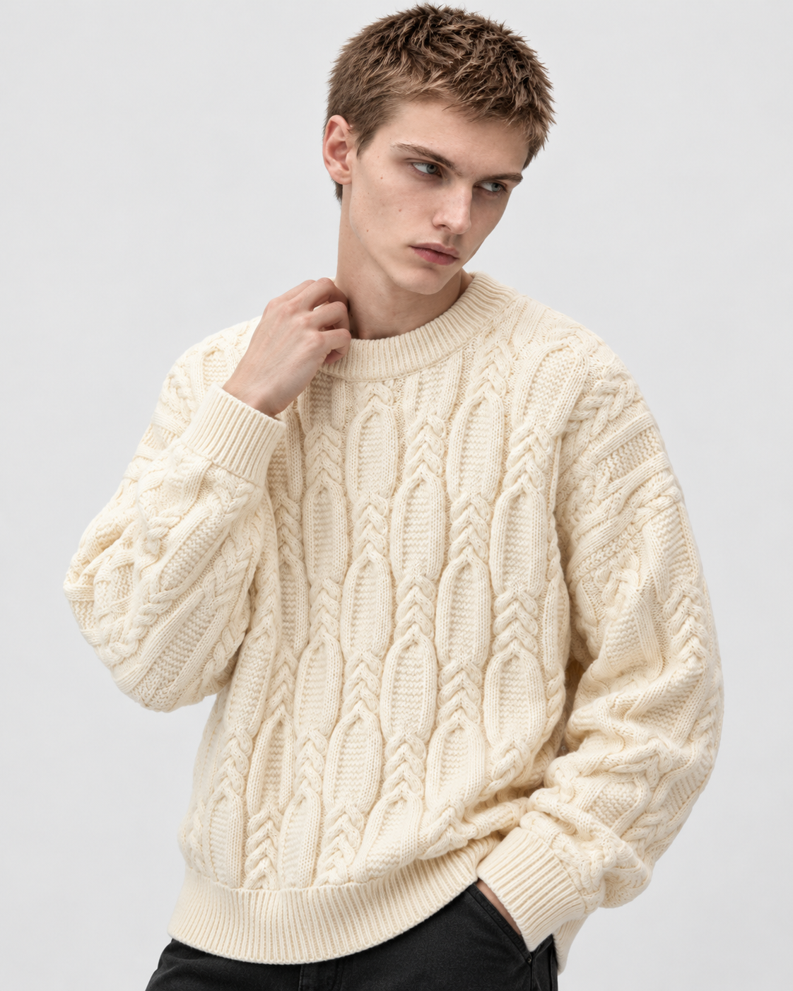 Image of Off-white | Male model wearing off-white cable-knit sweater, hand at collar in angled pose