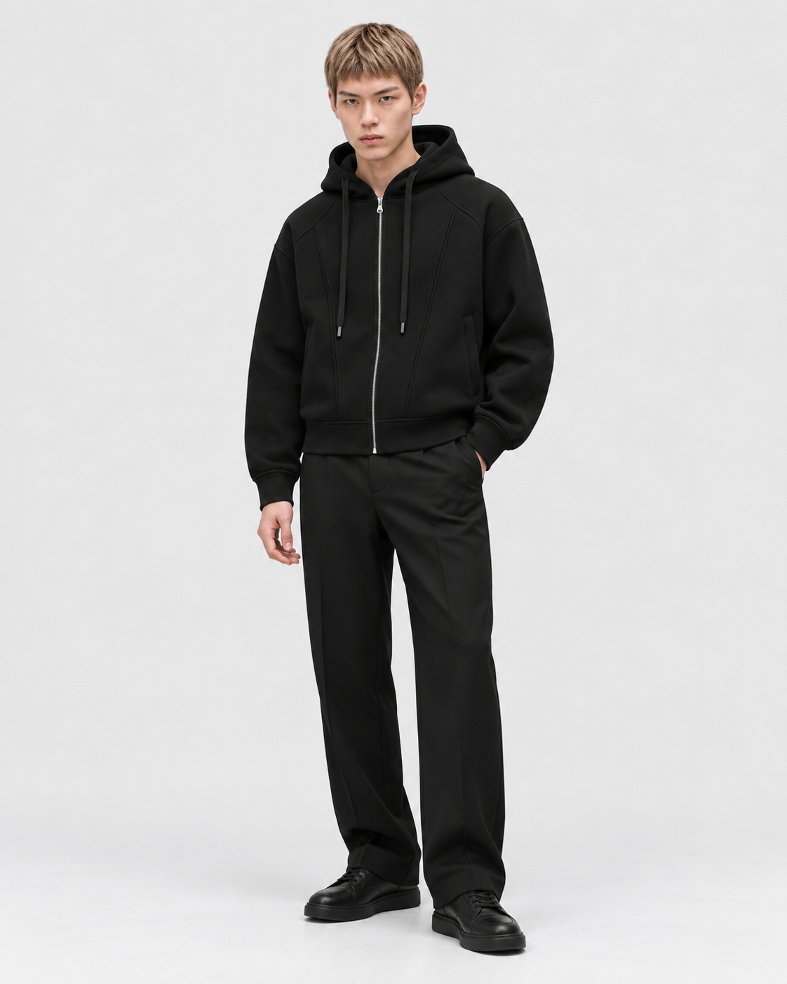 Black | Male model wearing the zip-up hoodie in a standing studio pose