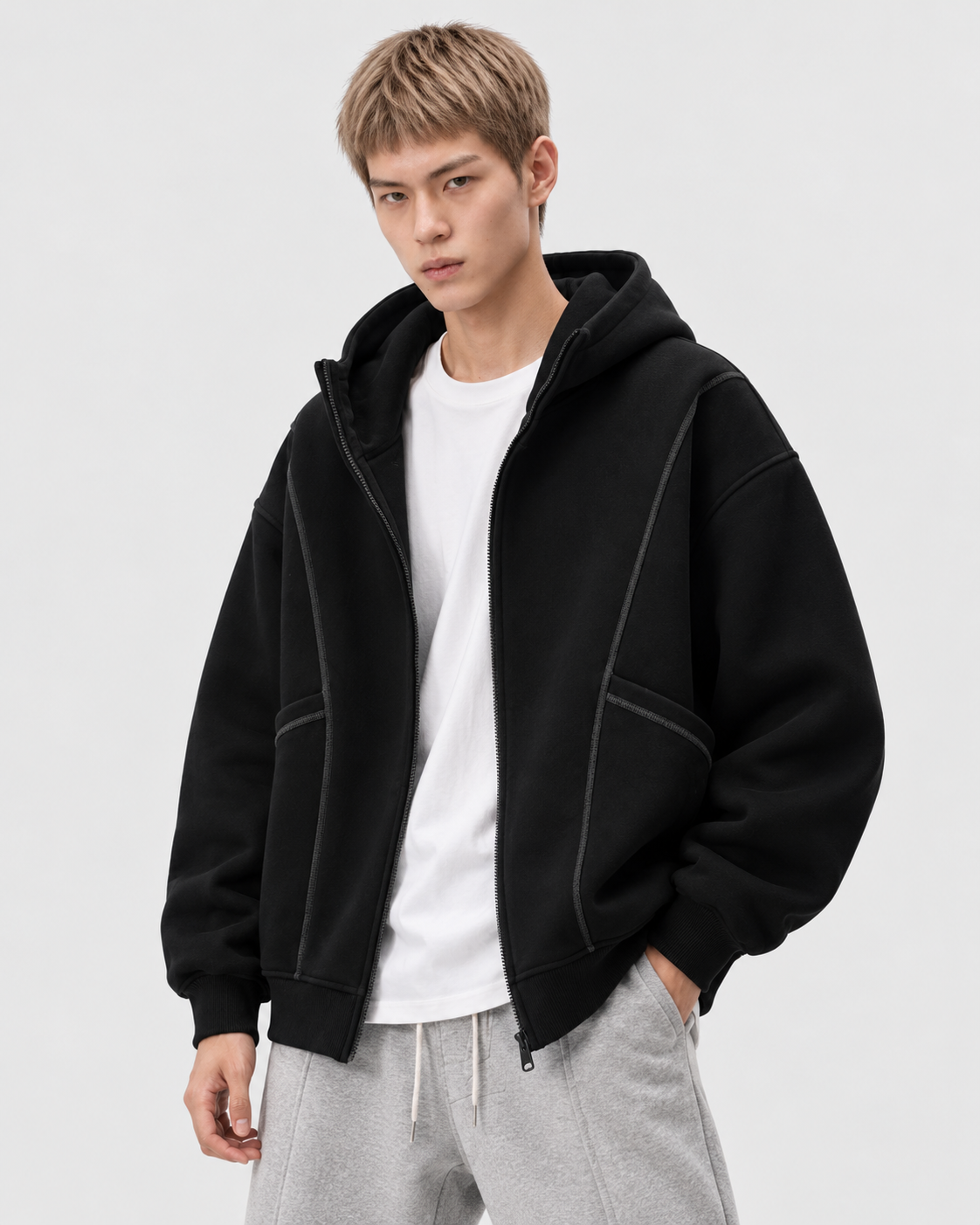 Image of Black | Male model wearing the black hooded zip-up sweatshirt over a white shirt in a standing pose