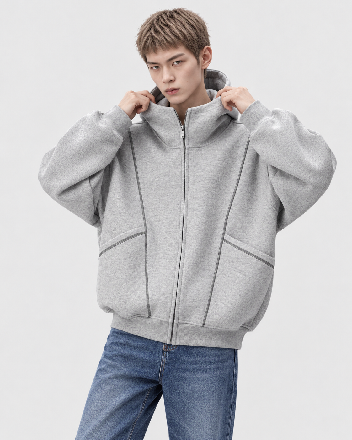 Gray | Male model wearing a gray hooded zip-up sweatshirt in a front-facing studio pose