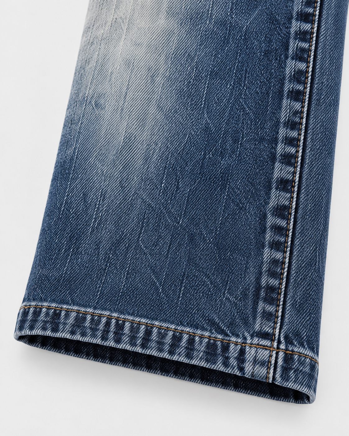 Blue | Close-up of stitched hem and faded denim on blue straight-leg jeans