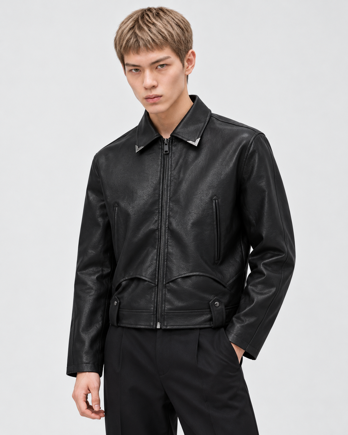 Image of Black | Male model wearing a black faux leather zip-up biker jacket in a standing studio pose