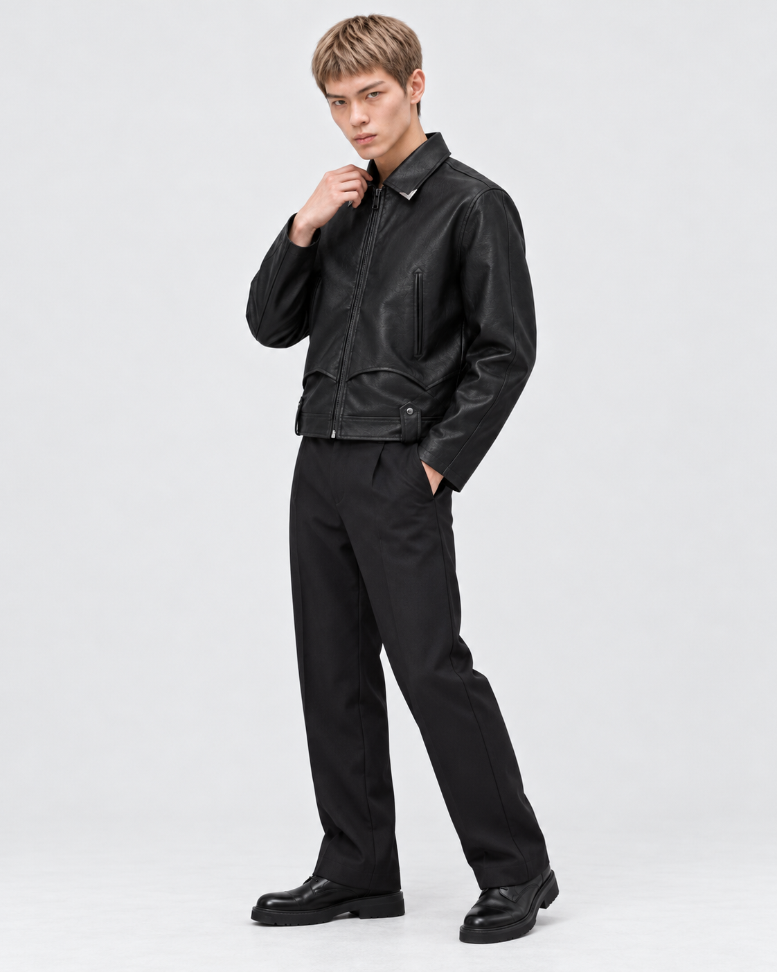 Image of Black | Male model wearing a black faux leather biker jacket in a full-length studio pose