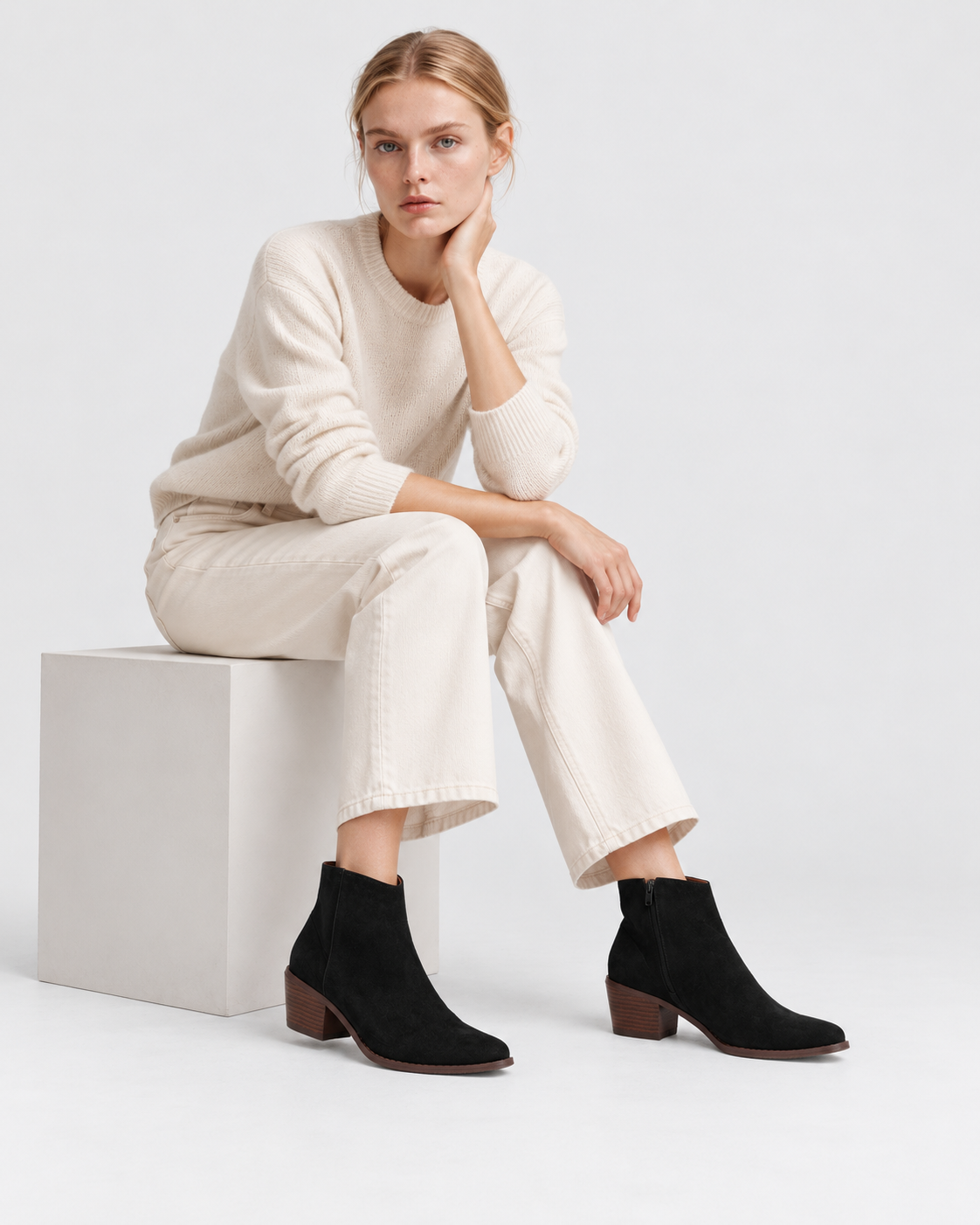 Image of Black | Seated model styling women's black pointed-toe heeled ankle boots