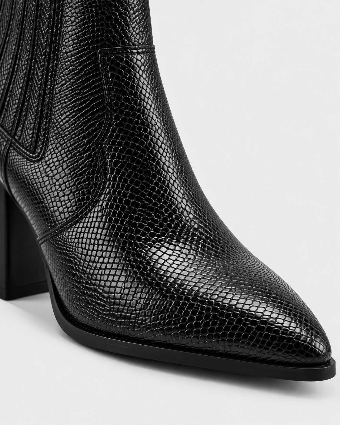 Black | Close-up of snakeskin-print upper and pointed toe on ankle boot