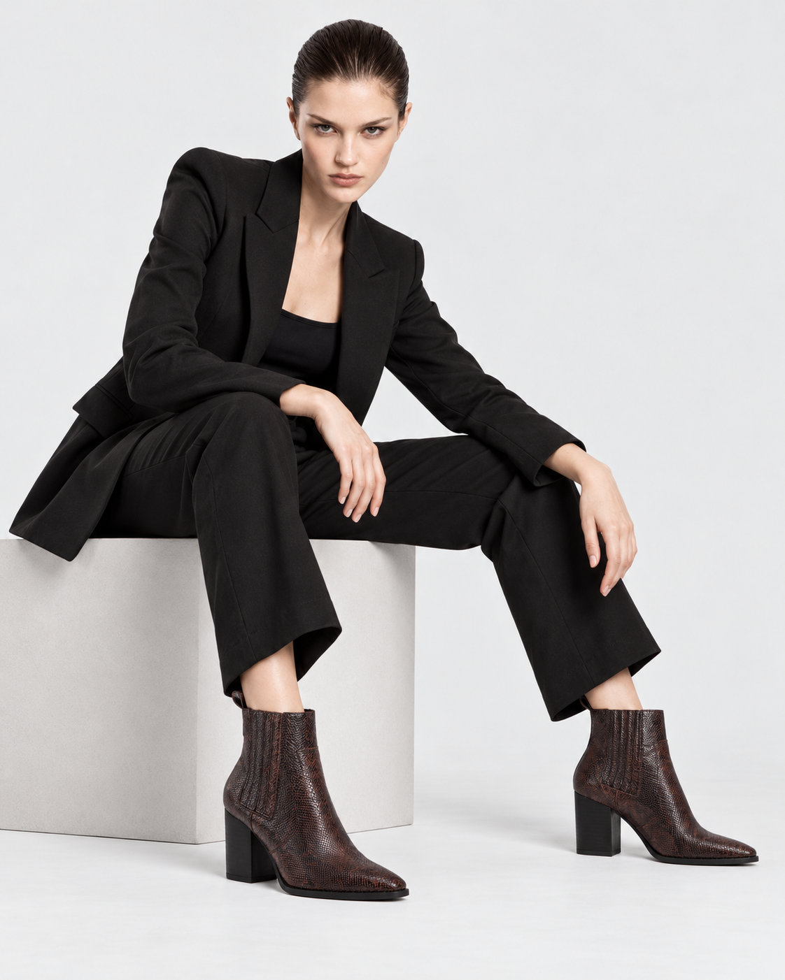 Image of Brown | Seated model wearing brown snakeskin-print pointed-toe ankle boots